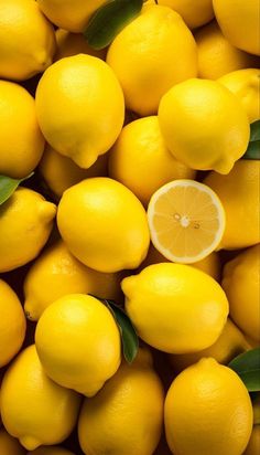 a pile of yellow lemons with leaves on top