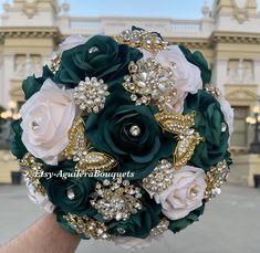 the bridal bouquet is green and white with pearls on it in front of a building