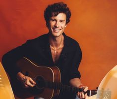 a man holding a guitar and smiling at the camera