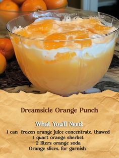 an orange punch recipe in a glass bowl on top of a table next to oranges