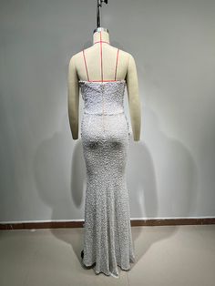 a mannequin wearing a white dress in front of a gray wall