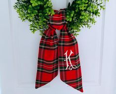 a red and black plaid bow with scissors on it hanging from the front door,