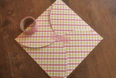 a pink and yellow checkered paper with a tape on it sitting on top of a wooden table