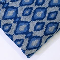 a blue and gray patterned pillow sitting on top of a white table