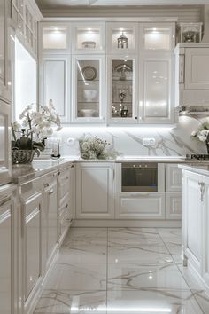 a kitchen with white cabinets and marble counter tops, along with vases filled with flowers