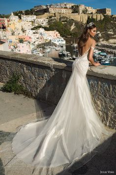 a woman in a wedding dress looking out over the water from a balcony overlooking a city