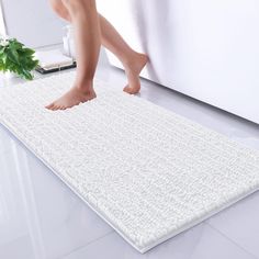 a person standing on top of a white rug in front of a bath room sink