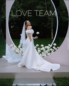 a woman in a white wedding dress standing next to flowers and the words love team