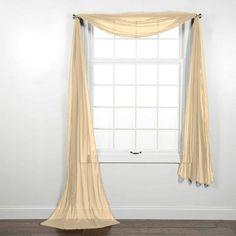 an empty room with a large window and sheer curtains on the windowsill, in front of a white wall