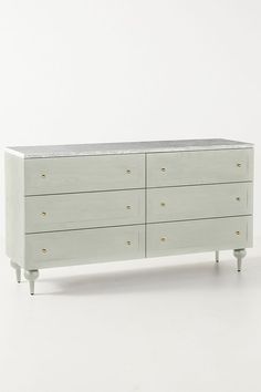 a white dresser with four drawers and two legs on each side, against a white background