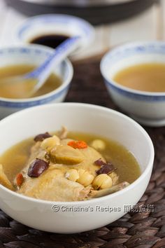 two bowls filled with soup on top of a woven place mat next to chopsticks