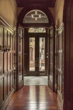 an empty hallway with wooden doors and tile flooring