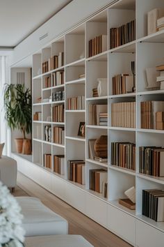 a living room filled with lots of white furniture and bookshelves full of books