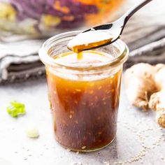 a spoon full of sauce sitting on top of a table next to garlic and ginger