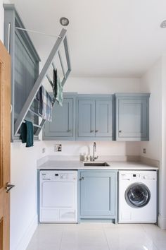 a washer and dryer in a small room with blue cupboards on the wall