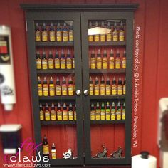 a display case filled with lots of bottles next to a wall mounted toilet paper dispenser