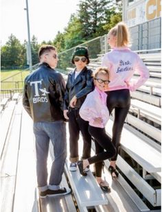 three people standing on bleachers with one person wearing a pink jacket and black leggings