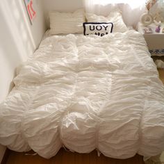 an unmade bed with white sheets and pillows on top of it in a small room