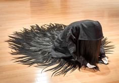 a black hat with long hair on the floor