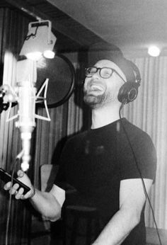 a man wearing headphones and holding a microphone in front of a recording equipment set