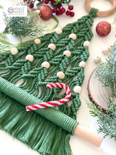 a green christmas tree made out of yarn with candy canes and ornaments around it