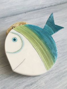 a ceramic fish with green and blue stripes on it