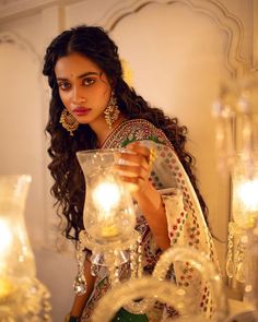 a woman is holding a vase with candles in it