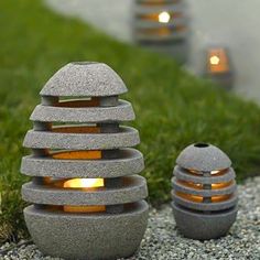 two stone lanterns sitting on top of a grass covered field next to a sidewalk with lights in them