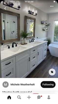 a large bathroom with two sinks and a bathtub in the middle, along with mirrors on the wall