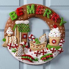 a christmas wreath with gingerbread houses and candy canes hanging on the front door