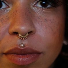 a close up of a woman's nose with a gold nose ring on her nose