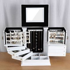 an open jewelry box sitting on top of a wooden table next to a framed mirror