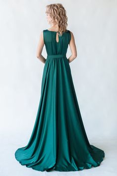 a woman in a long green dress standing back to the camera with her hands on her hips