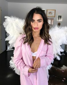 a woman with angel wings on her chest posing for a photo in front of a mirror