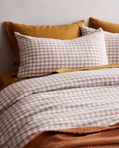 a bed with brown and white checkered sheets, pillows and blankets on top of it