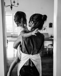 black and white photograph of two girls hugging each other in front of a door way