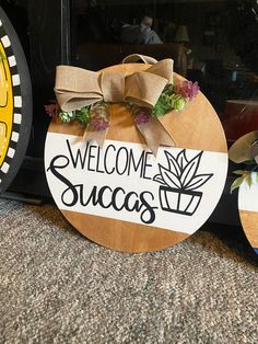 welcome succs sign sitting on the ground next to two clocks with flowers in them