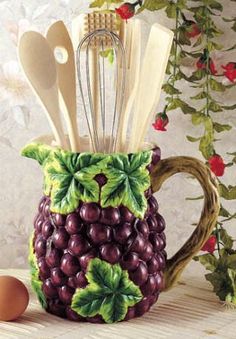 a ceramic pitcher with spoons and utensils in it