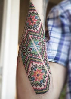 a man with a tattoo on his arm has a cross stitched design on it