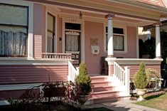 a pink house with white trim on the front porch