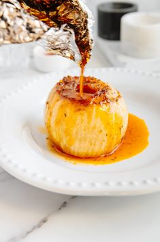 someone is pouring sauce on an apple covered in caramelized sugar and drizzled with cinnamon