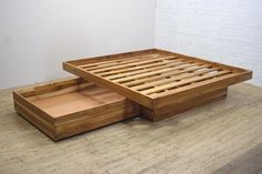 a wooden bed frame with two trays on the bottom and one drawer underneath it