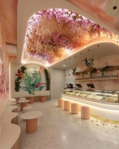 the interior of a flower shop with pink flowers hanging from the ceiling and white stools