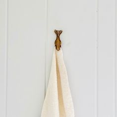 a towel hanging on the side of a white door with a wooden hook in it