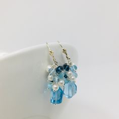 One of a kind Blue Topaz Cluster Earrings, are a perfect way to add a burst of color to any outfit. The fabulous array of colored gems include Sky Blue Topaz, Larimar, London Blue Topaz and Small Freshwater Pearls. This beautiful bouquet of gems sits on top of a unique asymmetrical large Sky Blue Topaz gemstone. Sterling Silver findings, lever back Earwires with a 2 inch drop length. Each set is personally handcrafted , so no two sets are identical. Handmade and designed in Stuart, FL and shipped from the US * In order to create unique and distinctive pieces, I use diverse shapes of natural gems to ensure that no two pieces are exactly the same. As such, each gem in hand-picked and inspected to ensure quality. However, I cannot create exact replications of any piece due to the natural vari Light Blue Gemstone Earrings - Fine Jewelry, Blue Briolette Earrings Fine Jewelry, Blue Gemstone Dangle Earrings, Blue Gemstone Crystal Drop Earrings, Blue Topaz Earrings With Gemstone Accents, Blue Gemstone Drop Earrings, Blue Topaz Teardrop Earrings, Blue Faceted Dangle Earrings, Blue Topaz Briolette Gemstone Earrings