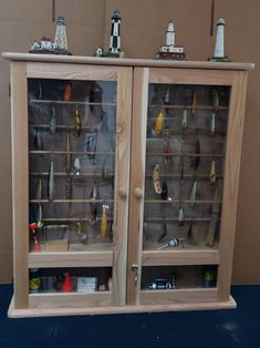 two glass doors with fishing lures on the bottom and inside, in front of a brown wall