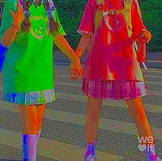 two girls are walking down the street holding hands and one is wearing bright colored clothing