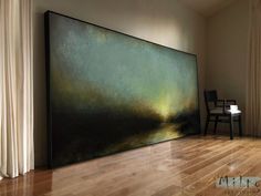 a large painting sitting on top of a hard wood floor next to a white chair