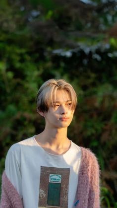 a young man with blonde hair wearing a white t - shirt and pink cardigan