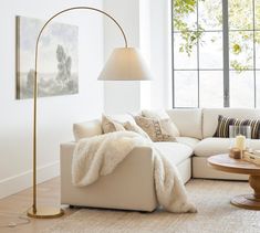 a living room filled with furniture and a tall lamp next to a large painting on the wall